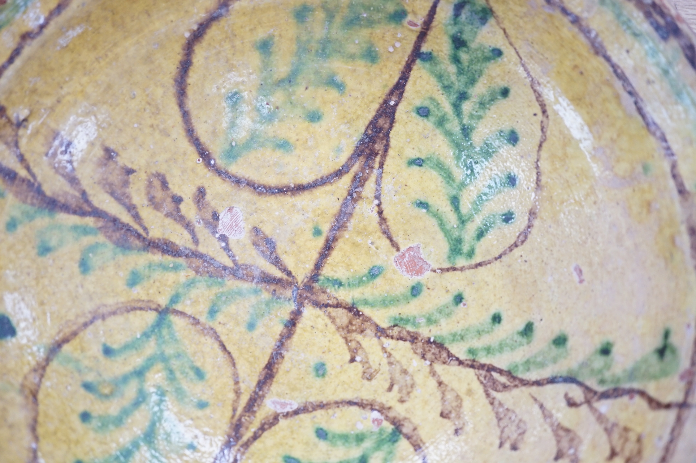 A group of Mediterranean slip decorated pottery dishes, a jar and cover and a bowl, predominantly with yellow and green grounds, the largest 26cm in diameter